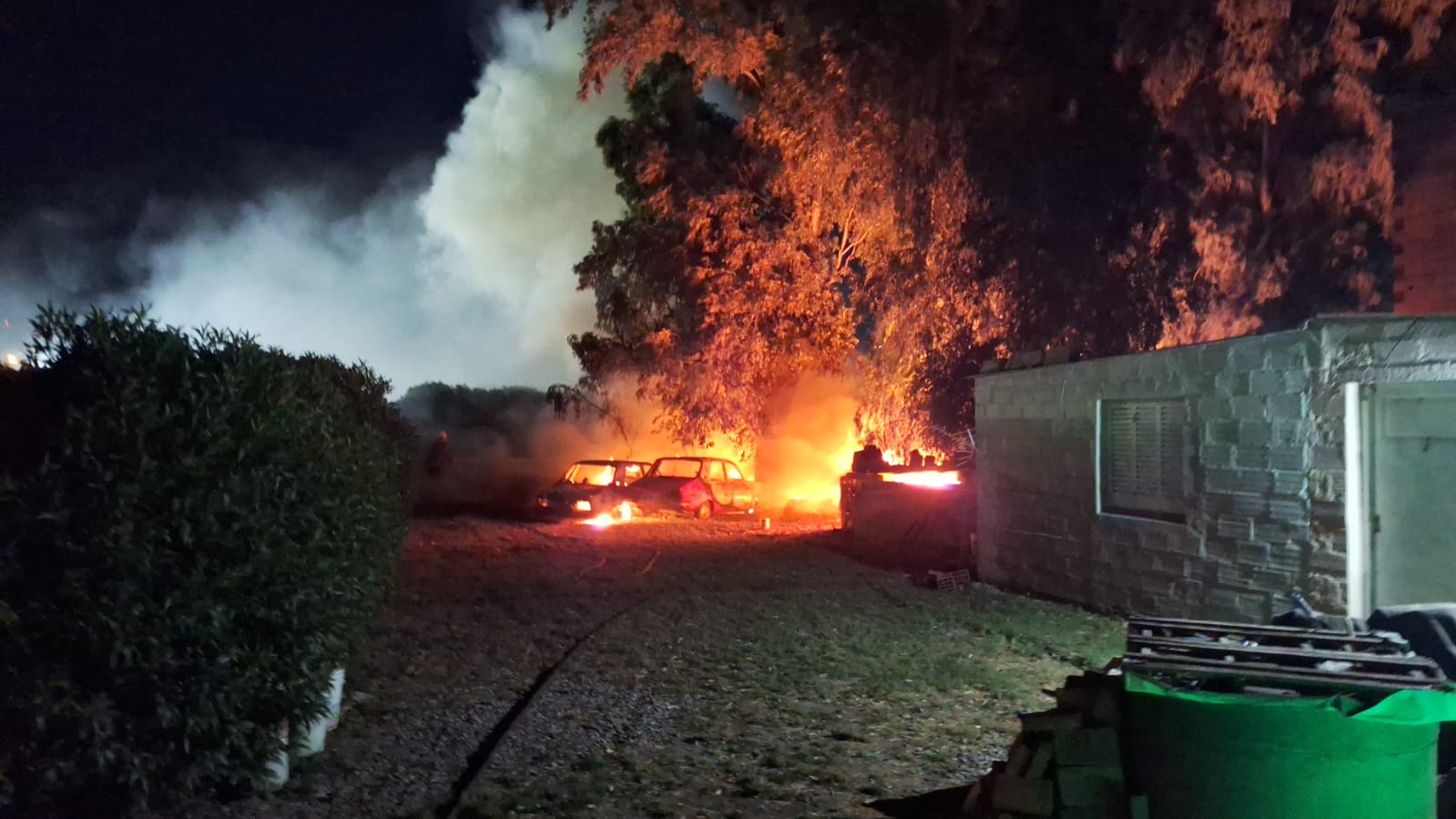 Dos autos envueltos en llamas en la parte trasera de una casa